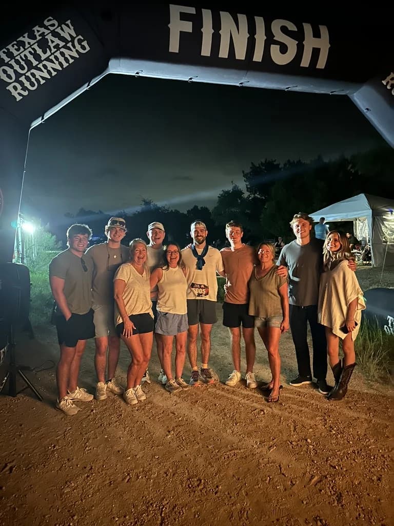 Dylan with family and friends under the finish arch at night.