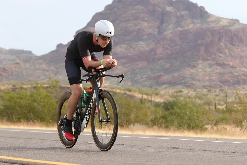 Dylan on a time-trial bike on the desert bike course, mountains behind.
