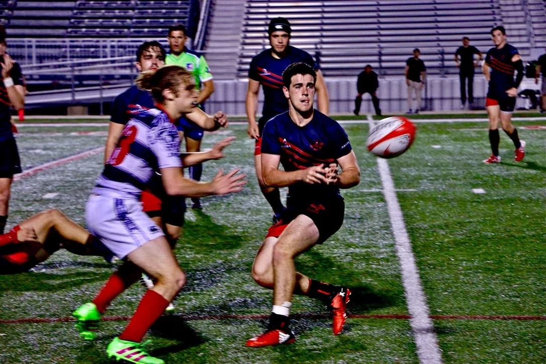 A Lake Travis player passes the ball out of contact during a night match.